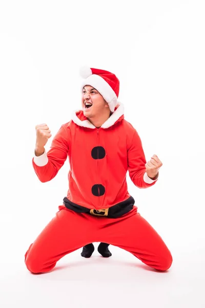 Mutlu genç adam Noel Baba'ya giymek beyaz arka plan üzerinde izole diz kayar — Stok fotoğraf