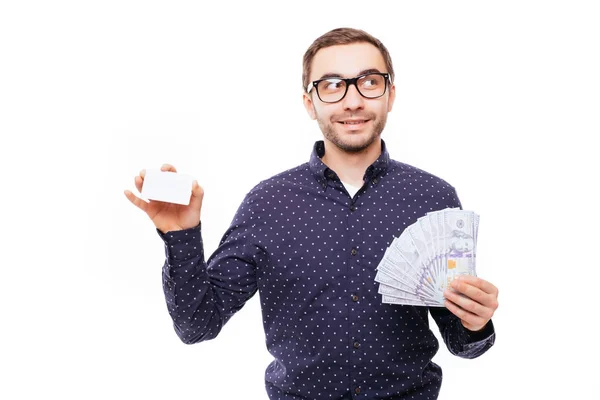 Full längd porträtt av en lyckligt leende man håller massa pengar sedlar och visar kreditkort isolerade över vit bakgrund — Stockfoto