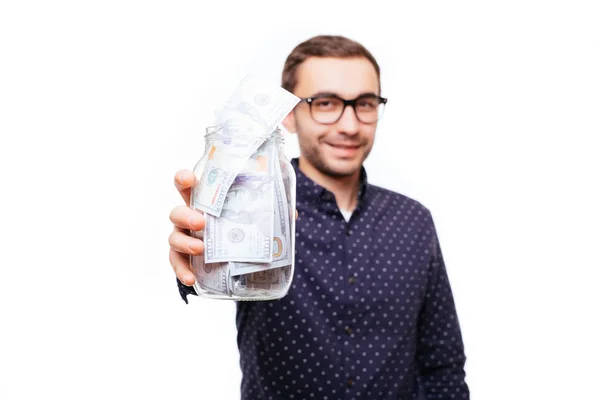 Retrato de un hombre satisfecho y confiado en vasos sosteniendo frasco de billetes de dinero aislados sobre blanco —  Fotos de Stock