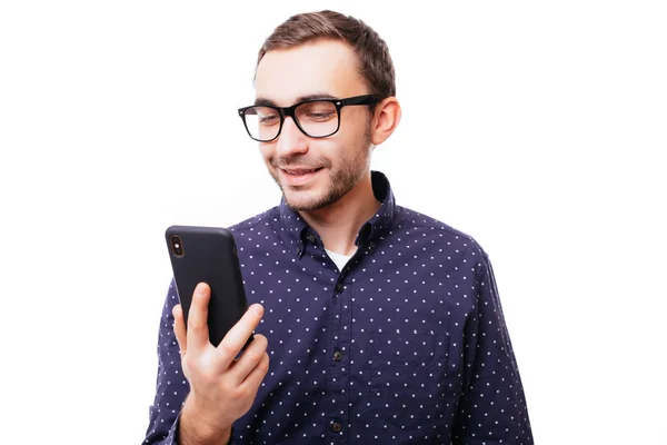 Molto felice sorridente giovane uomo adulto in camicia bianca guardando il suo telefono cellulare su sfondo bianco — Foto Stock