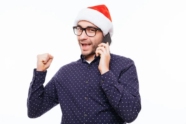 Casual jongeman in KERSTMUTS praten aan de telefoon en juichen. geïsoleerd op een witte achtergrond — Stockfoto