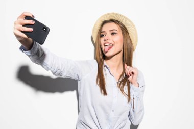 Ayakta ve beyaz arka plan üzerinde izole bir selfie alarak şapkalı gülümseyen çekici kadın portresi