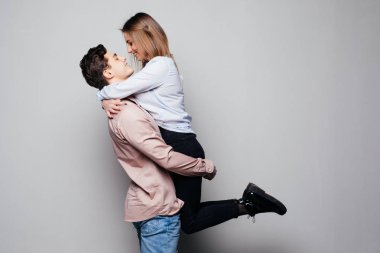 Mutlu adam güzel karısı gri arka plan üzerinde taşıyan.