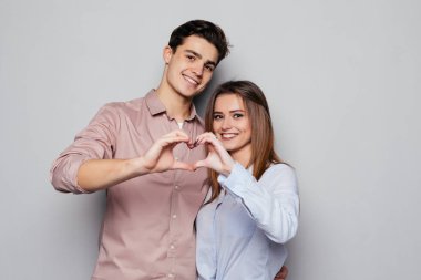 İki genç gülümseyen insanlar birbirlerine sarılma ve ellerini kullanarak haber yapma rahat giyim gri izole