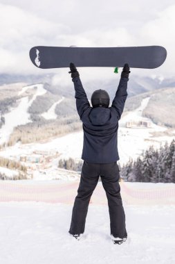 Mutlu adam snowboard ile ayakta dağlar tepenin üstünde onun Merkez over