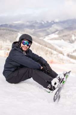 snowboard yüksek dağlarda yamaç kenarında oturur ve sürüş önce fotoğraf makinesi bakar