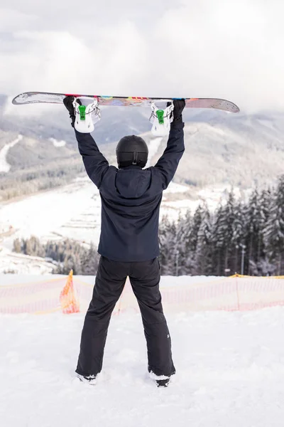 Szczęśliwy człowiek stojący z snowboard nad głową, na szczycie wzgórza, góry — Zdjęcie stockowe