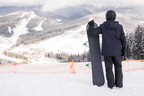 Vista trasera del deportista con tabla de snowboard viendo la pista de montar —  Fotos de Stock