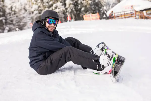 Snowboarder senta-se no alto das montanhas na borda da encosta e olha para a câmera antes do passeio — Fotografia de Stock