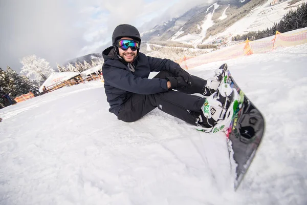 Snowboarder sitzt vor Fahrt auf Skipiste — Stockfoto
