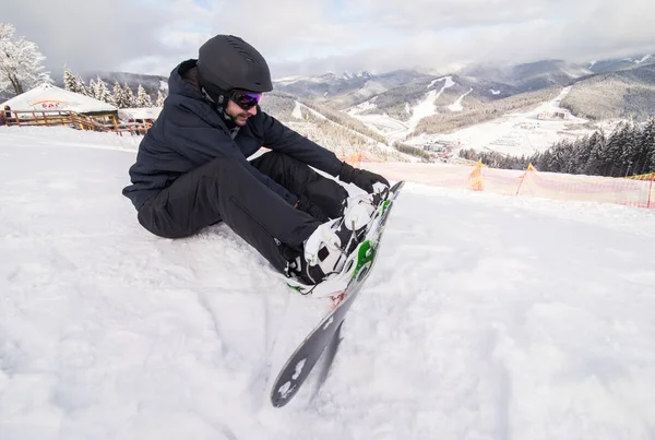 Snowboarder auf der Schanze Knöpfe vor Fahrt auf Schneehügel befestigen — Stockfoto