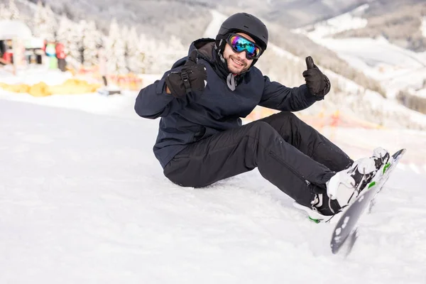 Snowboarder senta-se no alto das montanhas na borda da encosta e olha para a câmera antes do passeio — Fotografia de Stock