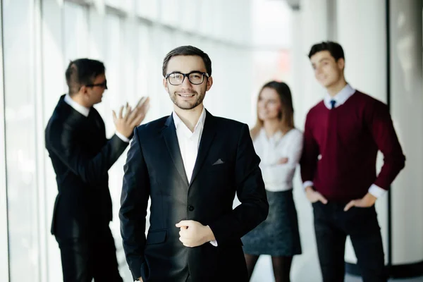 Uśmiechnięty i pewny siebie człowiek biznesu, stojąc przed dyskusji w biurze — Zdjęcie stockowe