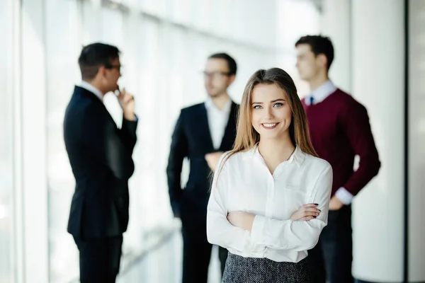 Happy young business woman standing in front of her team in office — Stock Photo, Image