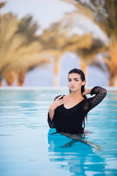 Hermosa chica es relajarse en una piscina infinita en vista de verano —  Fotos de Stock