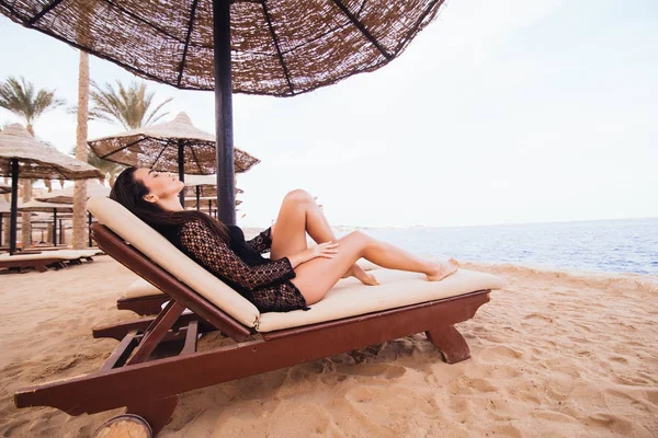 Gyönyörű fiatal nő, szexi lábak és a test, hogy a sun-tan egy nyugágyon a tenger parton fekvő. Nyári hivatása. — Stock Fotó