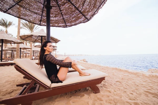 Красивая молодая женщина с сексуальными ногами и телом, загорающая на шезлонге на морском пляже. Летнее призвание . — стоковое фото
