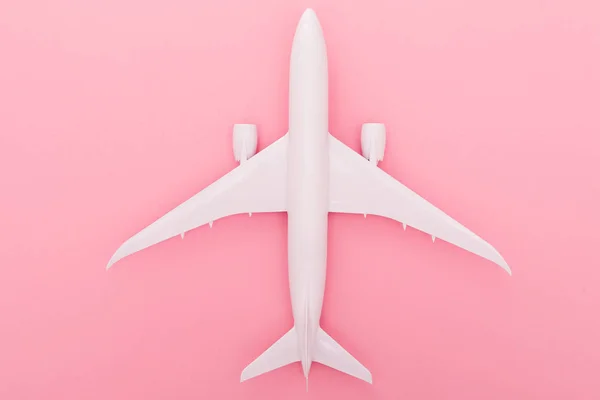 stock image White plane on light rose background. Top view