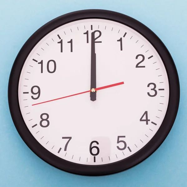 Настінний годинник ізольовано на синьому фоні. Дванадцята година — стокове фото