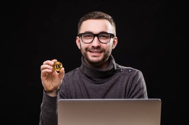 Siyah arka plan üzerinde izole dizüstü bilgisayar ile masa başında otururken bitcoin gösterilen mutlu bir işadamı portresi