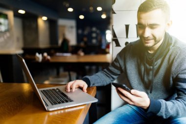 Kafede dizüstü metin ileti gönderme gülümseyen iş adamı. Adam göndermek veya seyir telefon mesaj okumak