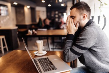 Laptop Cafe Shop baş ağrısı ile çalışan yakışıklı casual adam