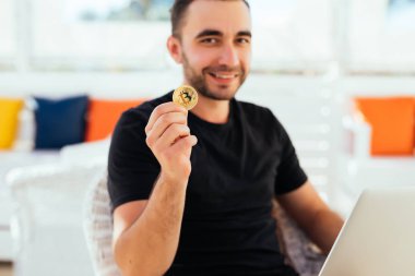 Dizüstü bilgisayar ile yakışıklı delikanlı bitcoin güverte üzerinde yaz meslek beack kafede oturan fotoğraf makinesinde işaret etti. Yaz meslek bitcoin değerini kontrol.
