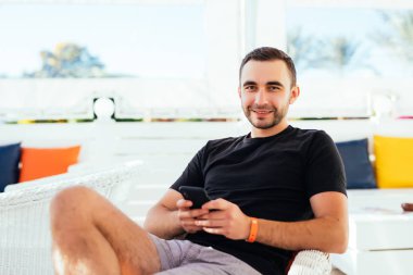 Yakışıklı adam tuping telefonu sahilde rahatlatıcı. Yaz meslek