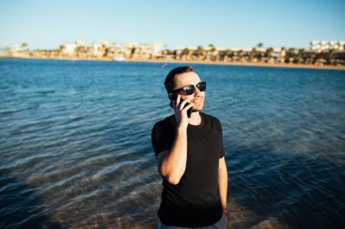 Selfie tatil sırasında cep telefonuyla deniz plajda alarak mutlu genç adam