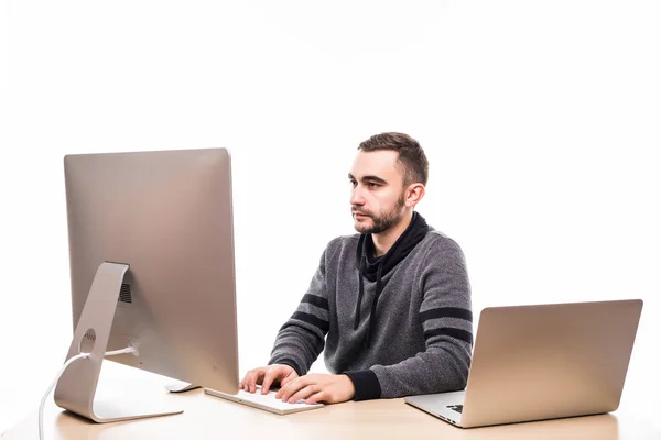 Empresário sentado atrás da mesa no trabalho, olhando para o monitor e laptop sobre fundo branco — Fotografia de Stock