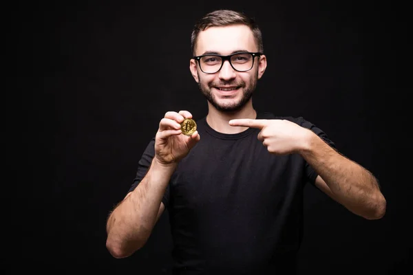 Szemüveget hord, rámutatott a bitcoin elszigetelt fekete háttér fekete inget fiatalember portréja — Stock Fotó