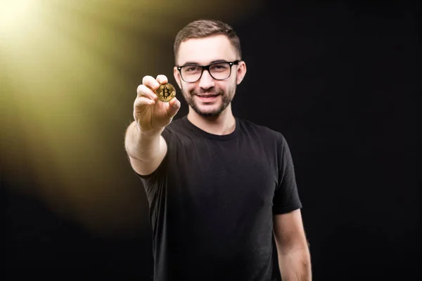 Retrato de joven hombre guapo en gafas de negro camisa puntiaguda bitcoin oro en la cámara aislada sobre fondo negro —  Fotos de Stock