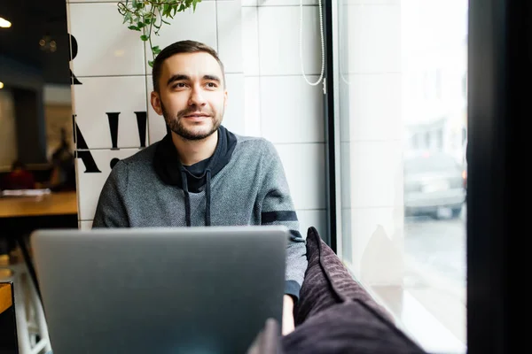 Yakışıklı sakallı adam kafede otururken dizüstü bilgisayarda çalışıyor — Stok fotoğraf