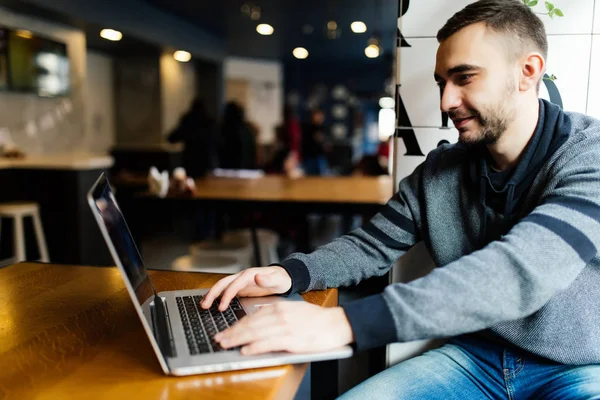 Estudiante sonriente usando laptop en la cafetería de la universidad. Freelancer trabajando con laptop en cafetería — Foto de Stock