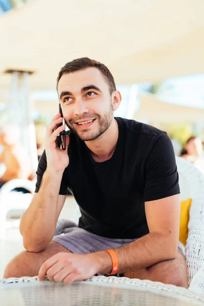 젊은 남자 여름 리조트 비치에서 야외 카페에서 휴대 전화로 전화 — 스톡 사진