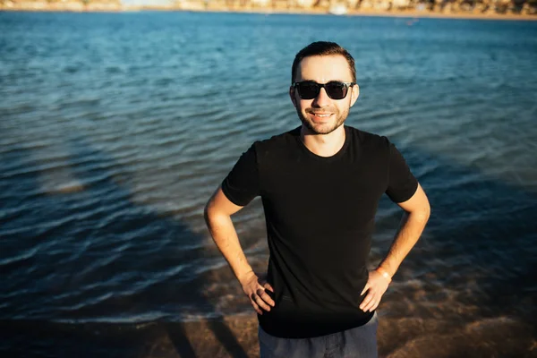 Young handsome man wearing spectacles and having fun on sea beach — Stok fotoğraf