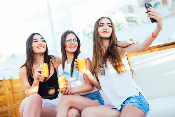 三个年轻的美女 手里拿着鸡尾酒 坐在休息室的沙发上 在暑假自拍 — 图库照片