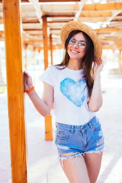 Mulher bonita com óculos de sol e chapéu de sol na moda banhos de sol na cadeira lounge perto da piscina no resort de férias — Fotografia de Stock