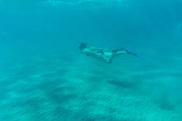 Mulher bonita subaquática em biquíni snorkels sobre recife de coral no mar — Fotografia de Stock
