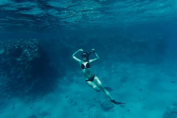 Mujer joven buceando en un respiro sostenido por un arrecife de coral mar — Foto de Stock