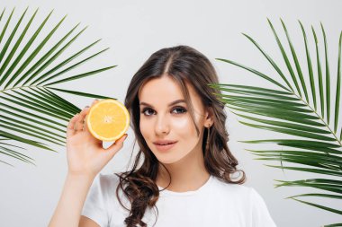 Beyaz arka plan üzerinde izole turuncu yeşil yaprakları ile poz ve holding esmer saçlı bir gülümseyen kadın Güzellik Portresi dilimlenmiş