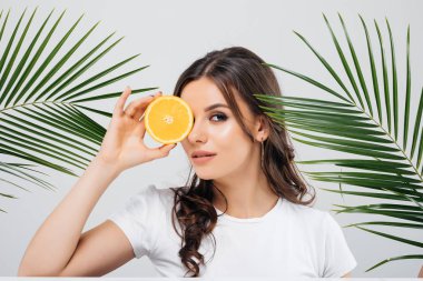 Beyaz arka plan üzerinde izole turuncu yeşil yaprakları ile poz ve holding esmer saçlı bir gülümseyen kadın Güzellik Portresi dilimlenmiş