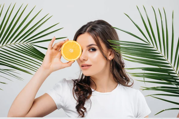 Beyaz arka plan üzerinde izole turuncu yeşil yaprakları ile poz ve holding esmer saçlı bir gülümseyen kadın Güzellik Portresi dilimlenmiş