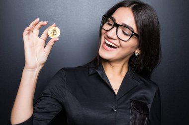 Gözlüklü genç başarılı kendine güvenen kadın siyah arka plan üzerine izole onun elinde bir altın bitcoin tutar