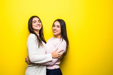 Sarı arka plan üzerinde izole sarılma Kazak giymiş iki mutlu kız portresi