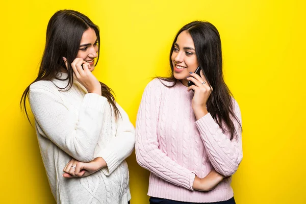 Retrato de uma feliz meninas falando em telefones celulares isolados sobre fundo amarelo — Fotografia de Stock