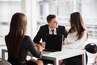 En iyi koşullar ile sözleşme. Kendine güvenen genç kadın belge ve gülümseme ile birlikte genç çift ofis masasında otururken ile işaret eden bazı ayrıntılarını açıklamak