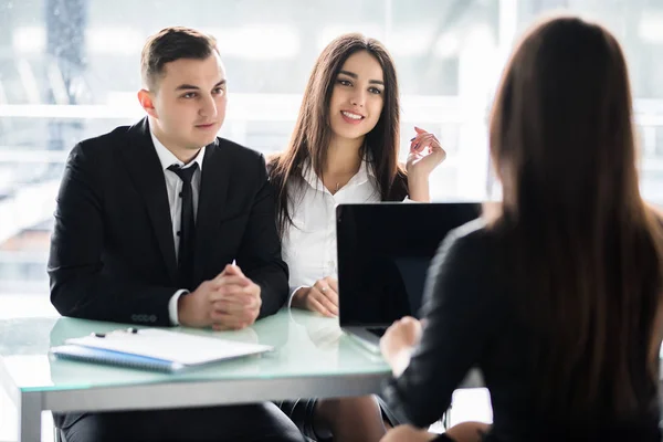 Försäljare talar med ett par av nöjda kunder som sitter i ett skrivbord på kontoret. Manager consalting par i office. — Stockfoto