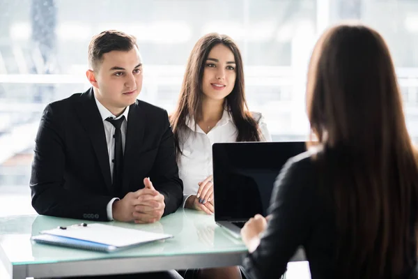 Försäljare talar med ett par av nöjda kunder som sitter i ett skrivbord på kontoret. Manager consalting par i office. — Stockfoto