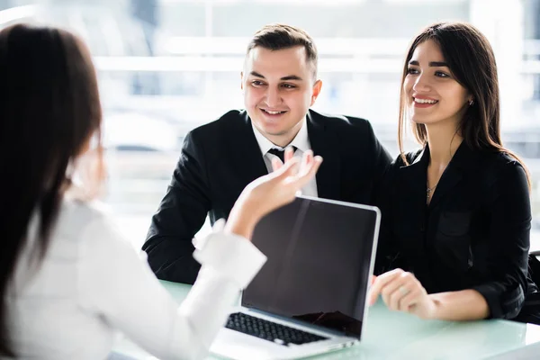 Pareja joven sentados juntos en el escritorio y escuchando a su asesor financiero — Foto de Stock